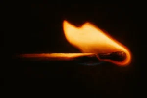 Close-up of a lit matchstick igniting in darkness, symbolizing the start of a potential home fire emergency scenario